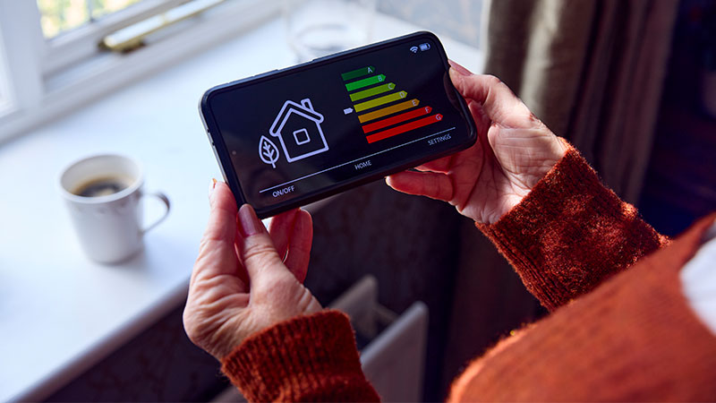 Illustration représentant l'impact du Diagnostic de performance électrique (DPE) sur la rénovation énergétique. L'image met en avant un monsieur et l'échelle de performance énergétique, entre ses mains, allant de G à A.