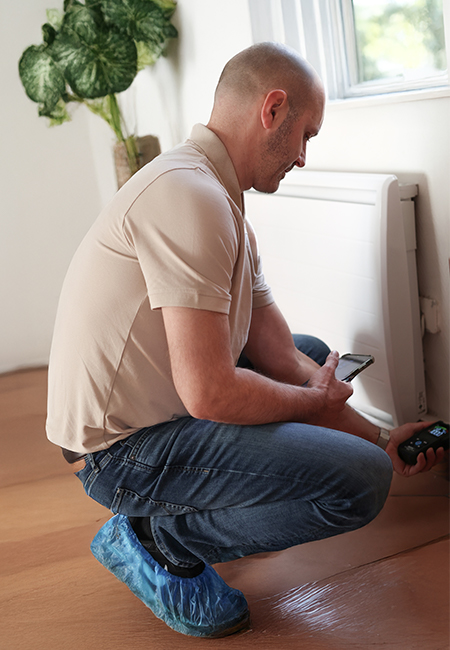 Technicien avec un appareil de mesure et des surchaussures de protection